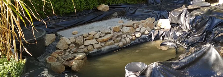 Teichfolie ausgelegt und teilweise mit Steinen bedeckt